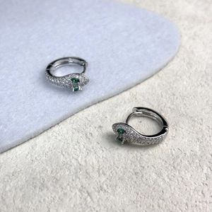 Détail de boucles d'oreilles serpent en argent avec oxydes de zirconium et yeux verts