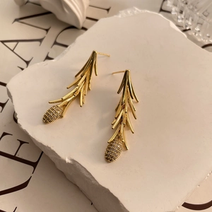 Detail of gold-plated pine branch earrings with white zircon pine cone charms on stone