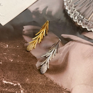 Detail of gold and silver pine branch earrings with zircon-encrusted cone drops