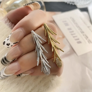 Detail of pine needle leaf earrings in gold and silver with zircon cone pendants