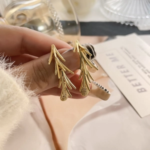 Macro detail of gold floral branch stud earrings with sparkling tassel drop accents