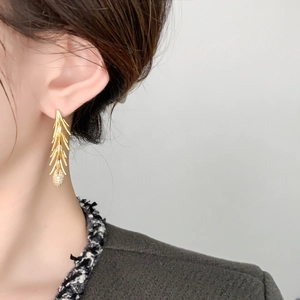 Close-up of elegant gold flower branch tassel earrings worn by a fashion model