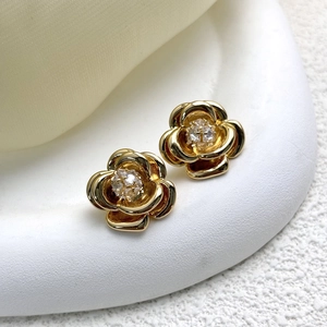 Macro detail of 18K gold plated camellia stud earrings with sparkling 5A zircon center