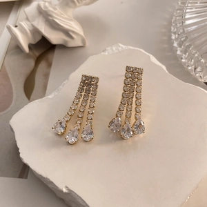 Detail of 18K gold-plated drop earrings with three rows of pavé zircons and pear-cut stones