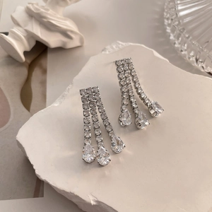 Macro detail of cascading silver tassel earrings featuring sparkling teardrop zircons