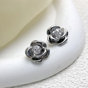 Macro shot of silver camellia earrings with 5A zircon inlay on white display
