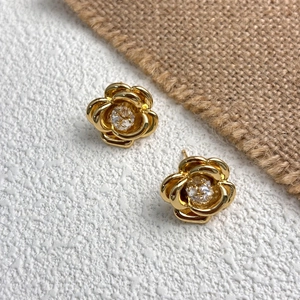 Detail of 18K gold plated camellia flower earrings with a sparkling zircon center stone