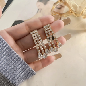 Detail of gold long tassel earrings with sparkling crystals and teardrop zirconia pendants