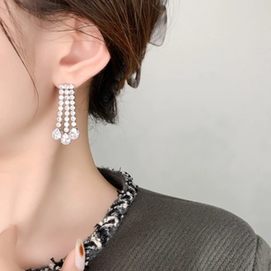 Close-up of silver tassel earrings with micro-paved diamonds and pear-cut zircon drops