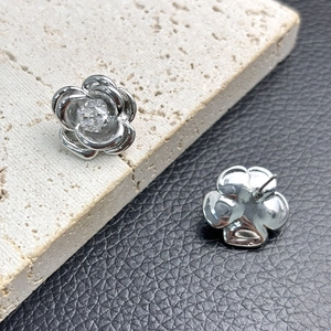 Macro shot of silver camellia earrings with 5A cubic zirconia on stone and leather