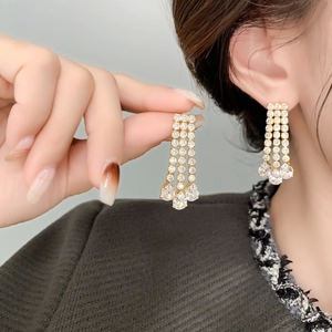 Close-up of elegant gold tassel earrings with shimmering crystals and pear-shaped drops