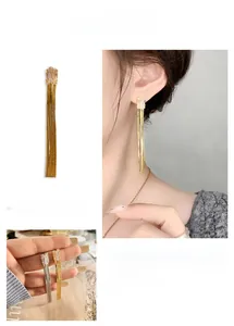 Détail de boucles d'oreilles pendantes à pampilles en cristal clair doré et argent