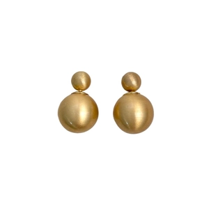 Macro shot of matte gold double-ball earrings with elegant brushed metal texture