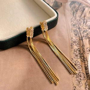 Vue macro de boucles d'oreilles longues à glands dorés avec cristaux sur satin