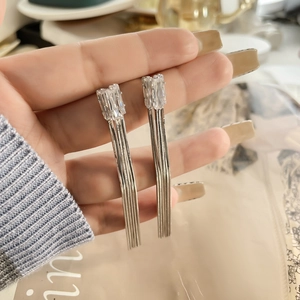Gros plan de boucles d'oreilles à pompons longs avec cristaux et chaînes pendantes