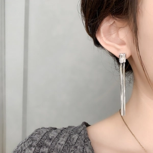 Gros plan de longues boucles d'oreilles à pompons argentés avec zircon sur mannequin chic