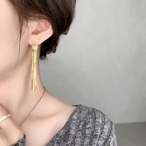Vue détaillée de boucles d'oreilles longues à pampilles dorées avec cristal carré