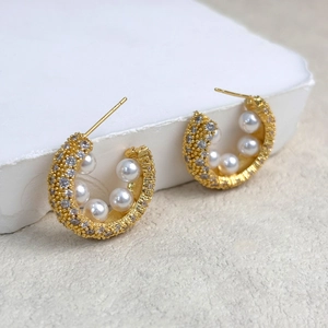 Macro shot of 18K gold plated C-shaped earrings with pearls and micro-set zircon accents
