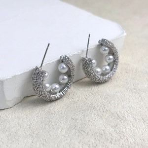 Detail of C-shaped earrings with micro-pave cubic zirconia and five white pearls