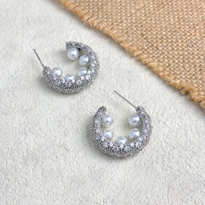 Detail of gold-plated C-shaped earrings with micro-paved zircons and white pearls