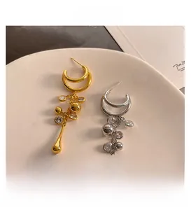 Detail of C-shaped hoop earrings with tassel pendants in gold and silver plating
