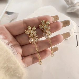 Detail of gold-plated floral earrings with shimmering zircons and long tassel pendants