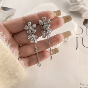 Macro detail of long flower tassel earrings with shimmering crystals and silver plating