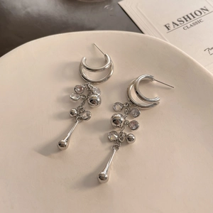 Macro shot of silver C-ring chain tassel earrings with sparkling rhinestones and metal beads