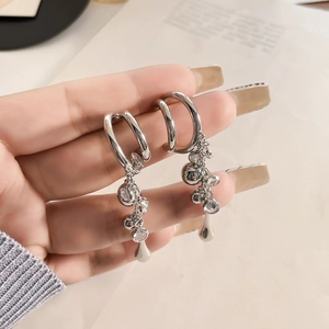 Detailed close-up of silver C-ring earrings with tassel chains and sparkling cubic zirconia
