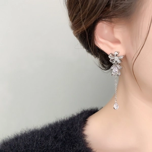 Macro shot of silver long tassel earrings with sparkling flower zircon details