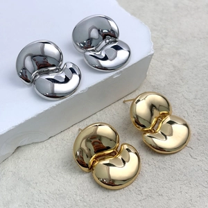 Macro detail of polished gold and silver bean earrings in a minimalist organic shape