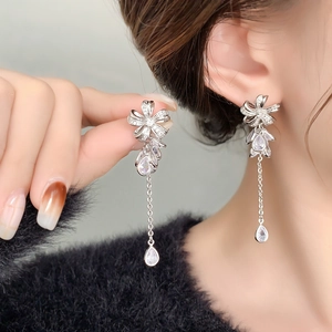Detail of elegant silver tassel earrings with zircon bow and sparkling teardrop stones