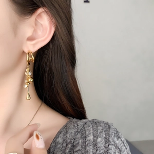Close-up of elegant long gold tassel earring with crystals and water-drop pendant