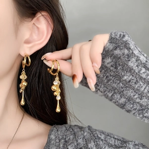 Detail of elegant gold drop earrings with tiered tassels and clear crystals on a model