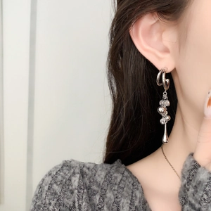 Detail of silver chain tassel earrings on model featuring crystal ring and drop pendants