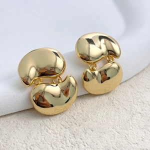 Macro shot of minimalist gold plated bean earrings with high polish mirror finish