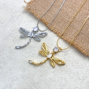 Macro detail of gold and silver dragonfly necklaces with sparkling crystal inlays
