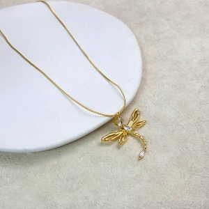 Macro detail of golden dragonfly pendant necklace with sparkling zircon stone settings