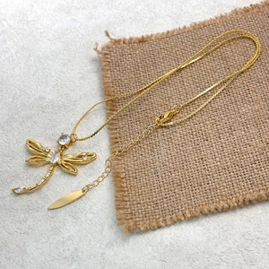 Detailed view of golden dragonfly pendant with white zircons and extension chain tag