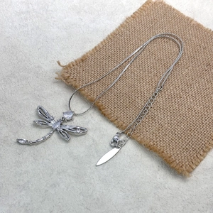 Macro detail of silver dragonfly pendant with clear zircon inlay and lobster clasp