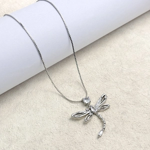 Macro shot of silver dragonfly pendant with inlaid cubic zirconia and delicate chain
