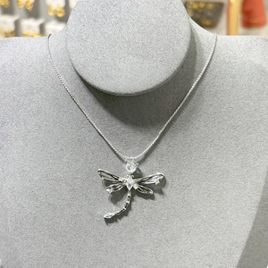 Detail of dragonfly pendant necklace featuring silver-tone metal and sparkling cubic zirconia