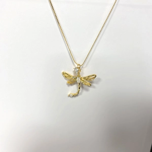 Detailed view of golden dragonfly pendant necklace with sparkling inlaid zircons