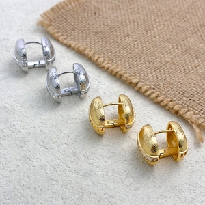 Macro detail of gold and silver square hoop earrings with textured brushed finish and zircons