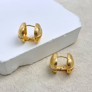 Luxurious gold textured hoop earrings with sparkling cubic zirconia on stone display
