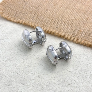 Detailed view of silver hoop earrings featuring vertical textured stripes and snap closure