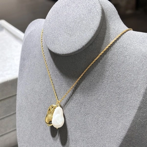 Collier chaîne torsadée dorée avec perle baroque et pendentif sur un présentoir