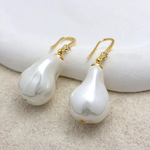 Détail macro de boucles d'oreilles en perles baroques avec crochets dorés et zircon