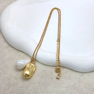 Détail du collier doré avec perle baroque et pendentif cacahuète en métal doré