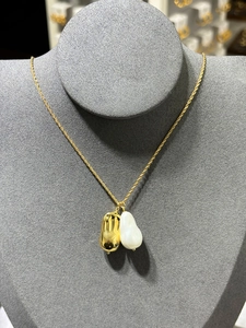 Détail du collier chaîne torsadée dorée avec perle baroque et pendentif fève poli